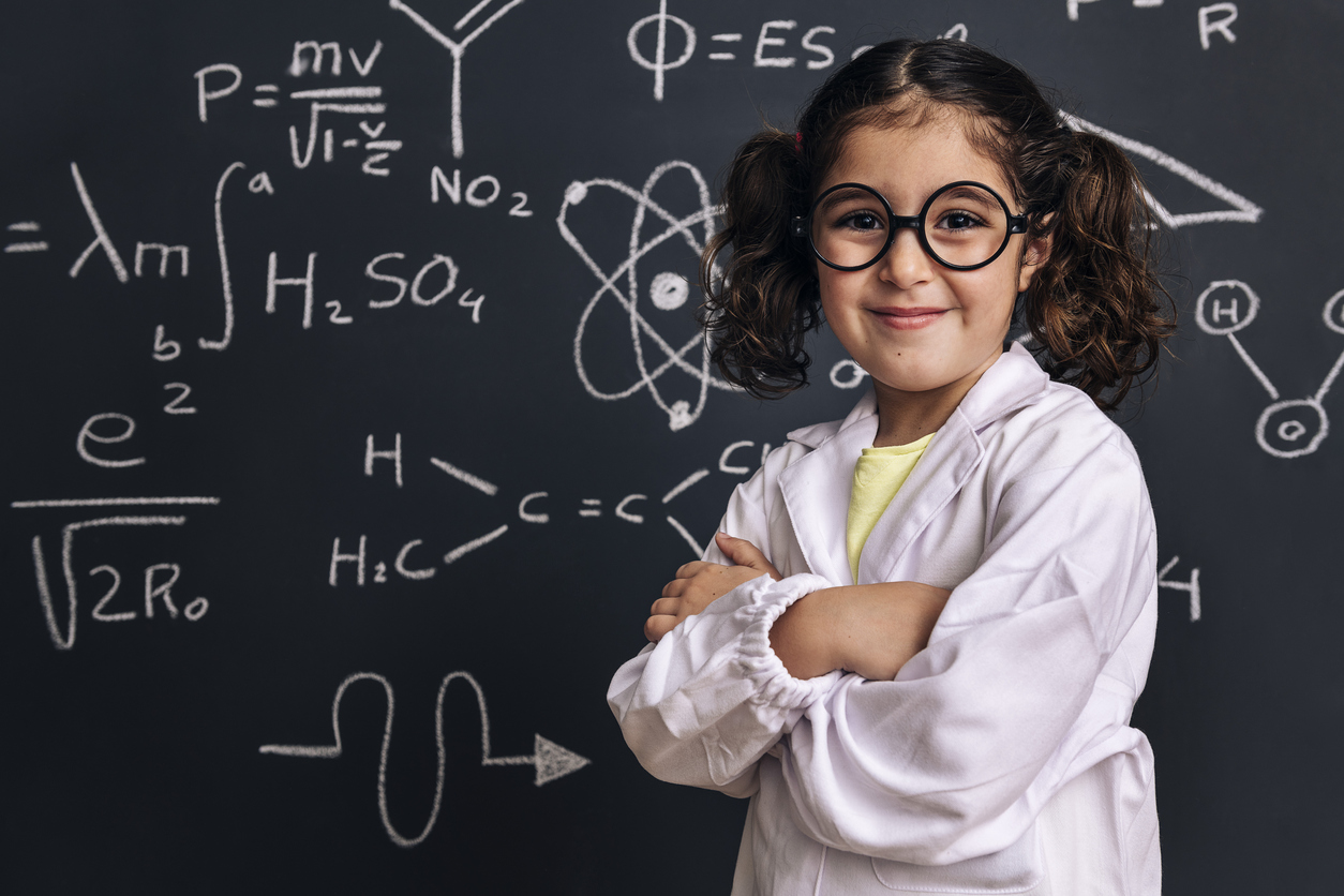 Bambina sorridente davanti a una lavagna piena di formule matematiche