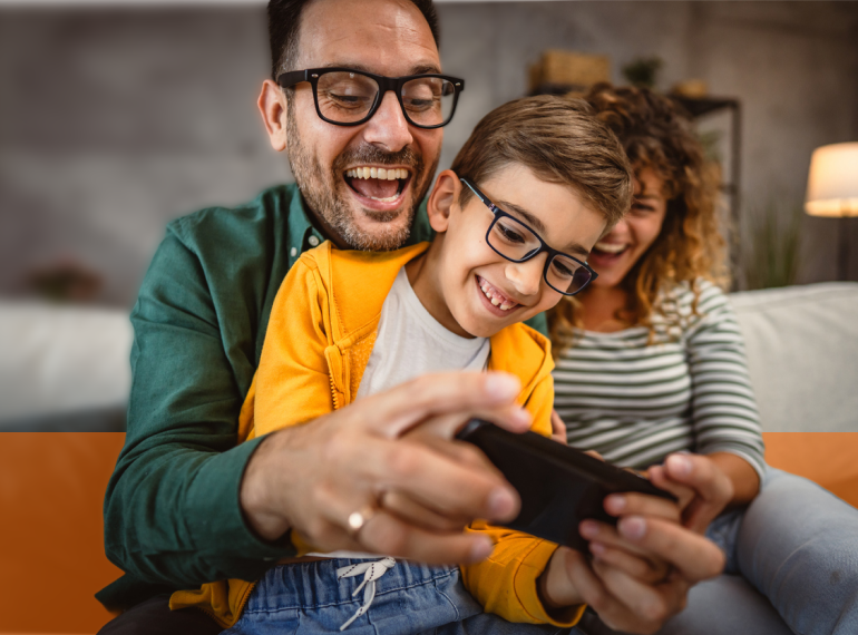 Padre madre e figlio giocano a un videogioco sul divano