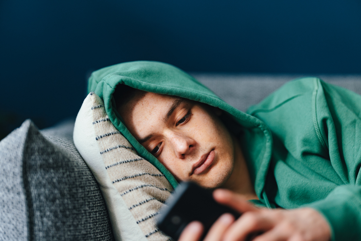 Adolescente triste che usa un telefono cellulare nella sua camera da letto