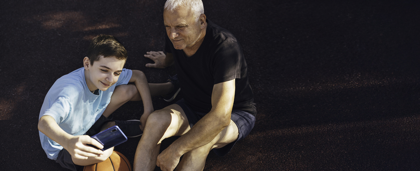 Un bambino insegna al nonno una funzione dello smartphone