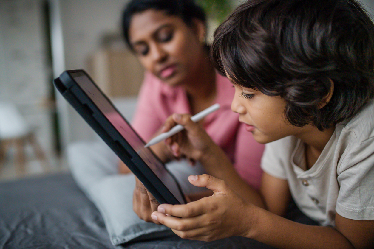 Un bambino usa il tablet in casa in compagnia di sua madre