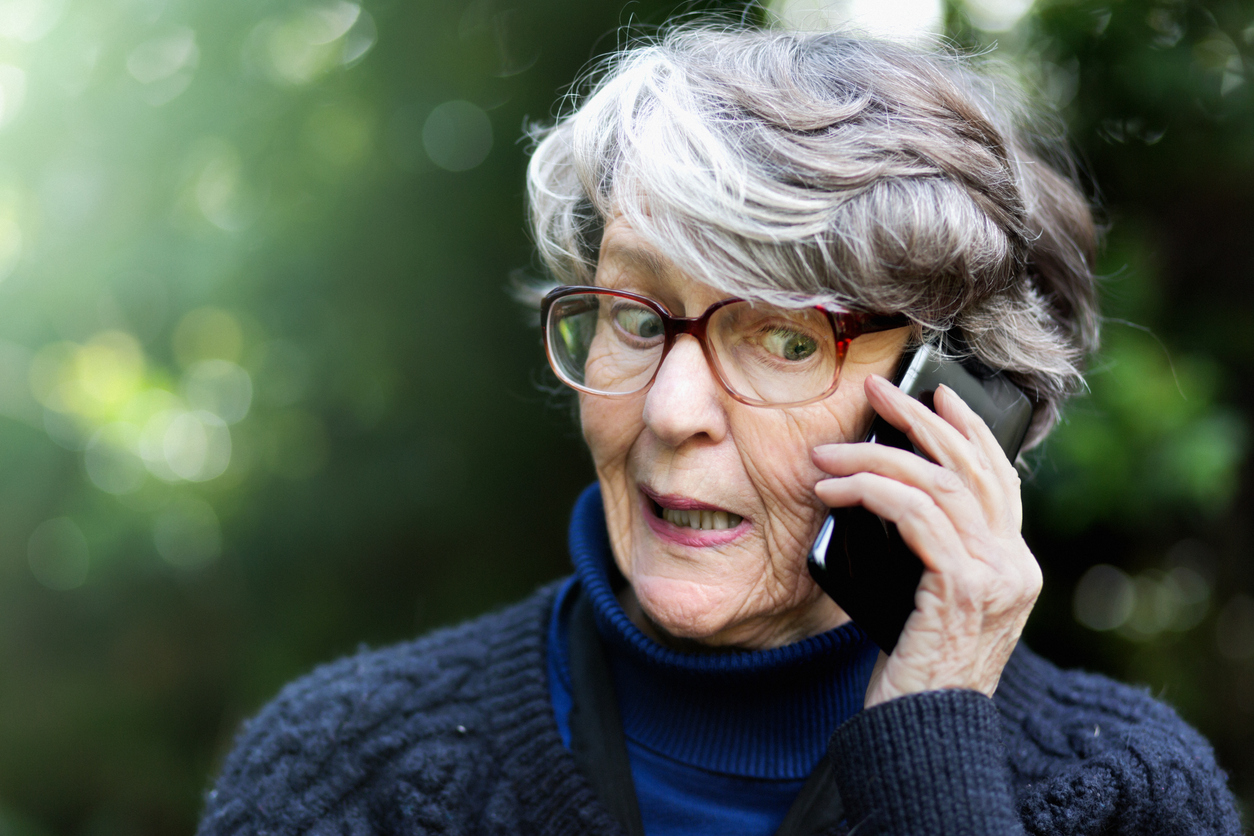 Donna anziana con sguardo diffidente risponde al telefono