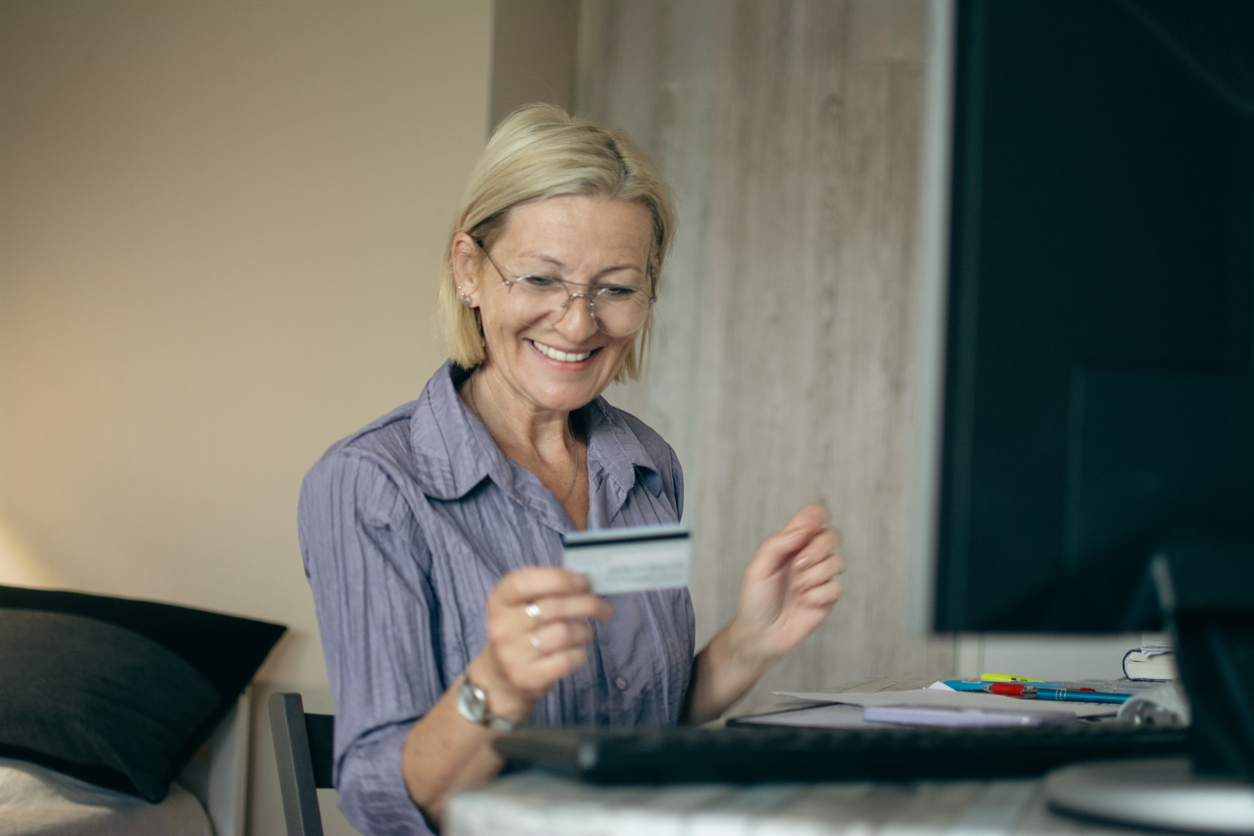 Donna matura usa la carta di credito per fare acquisti online da casa