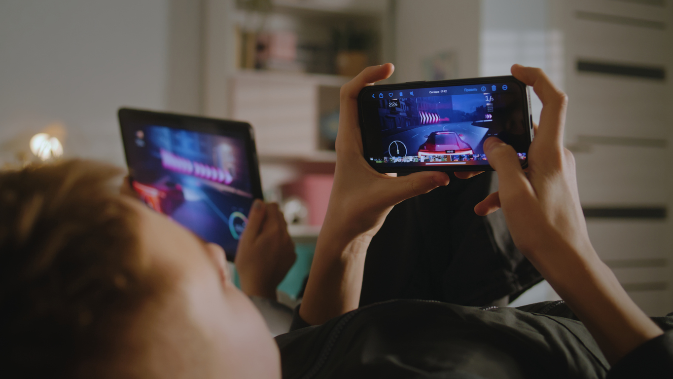Due fratelli giocano con i videogiochi insieme sdraiati su un letto