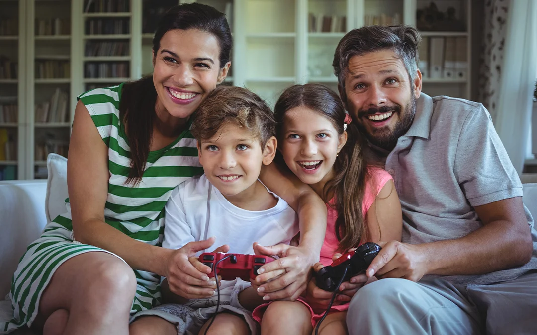 Una famiglia seduta sul divano gioca a un videogioco con dispositivo digitale