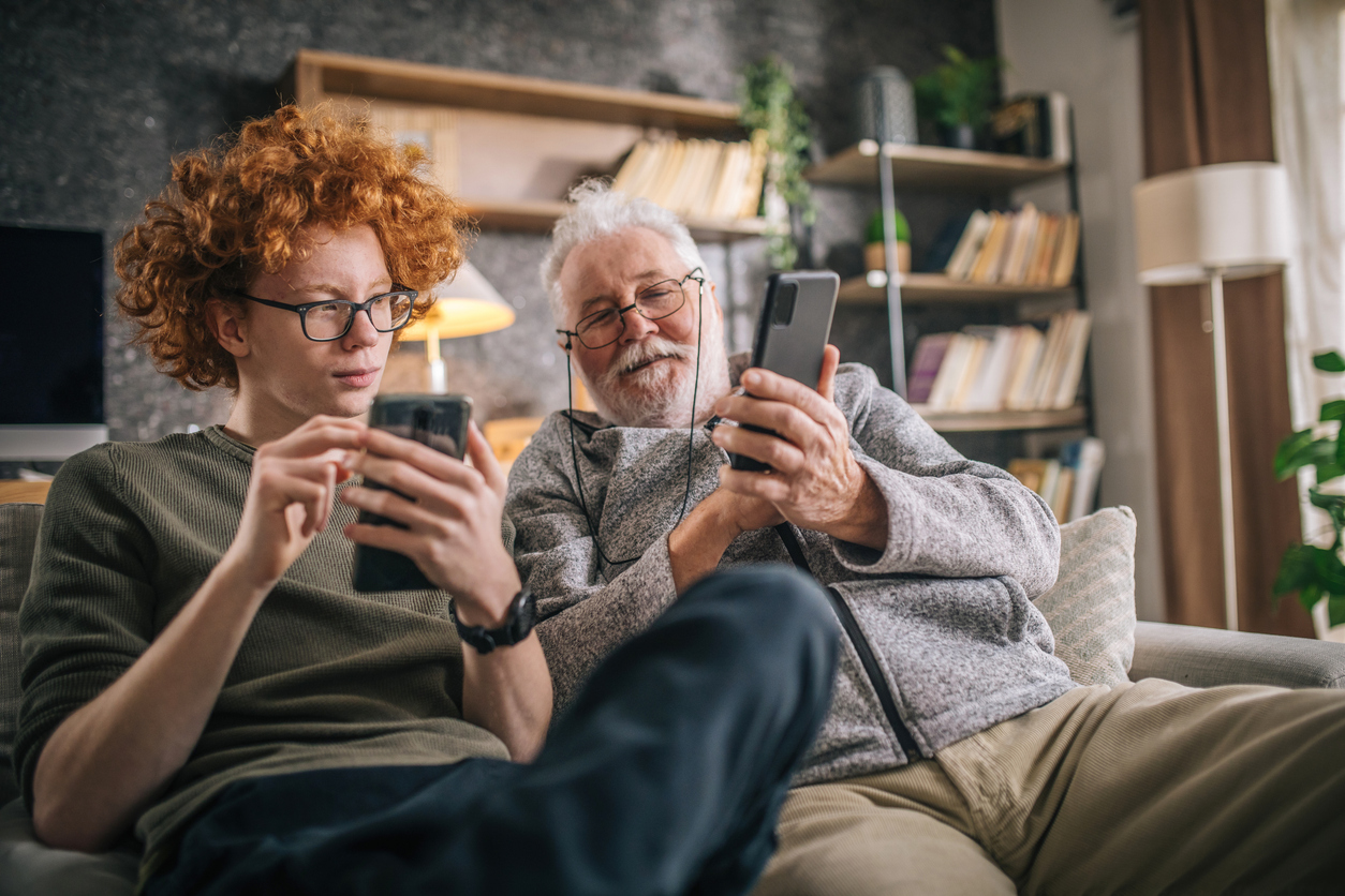 Nonno sul divano con in mano un cellulare parla con nipote