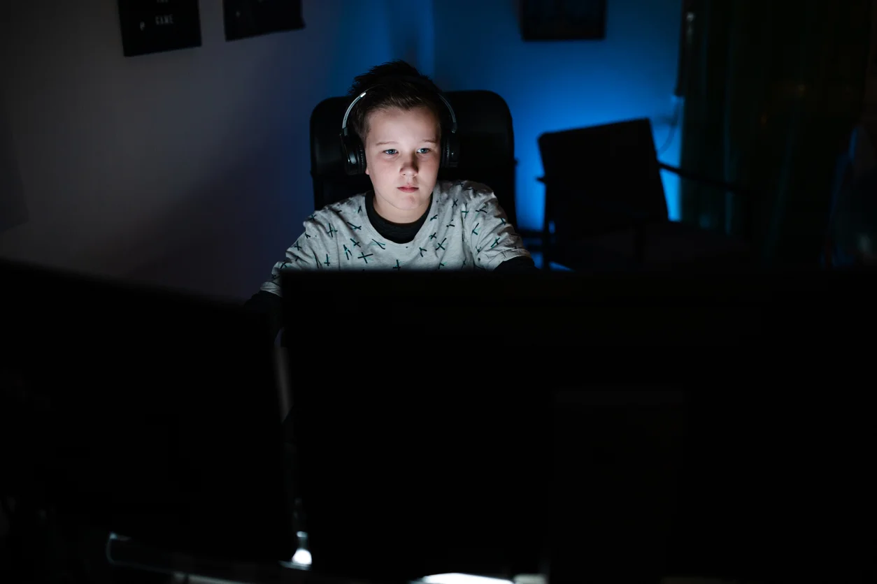 Un ragazzino seduto davanti a un computer con cuffie