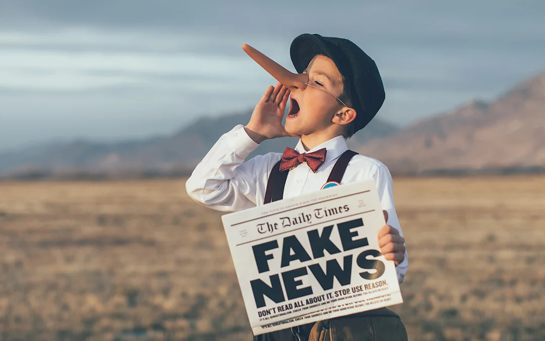 Un ragazzino con naso finto tiene in mano un giornale con la scritta fake news