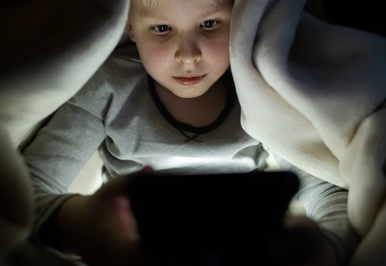Un giovane ragazzino guarda uno smartphone