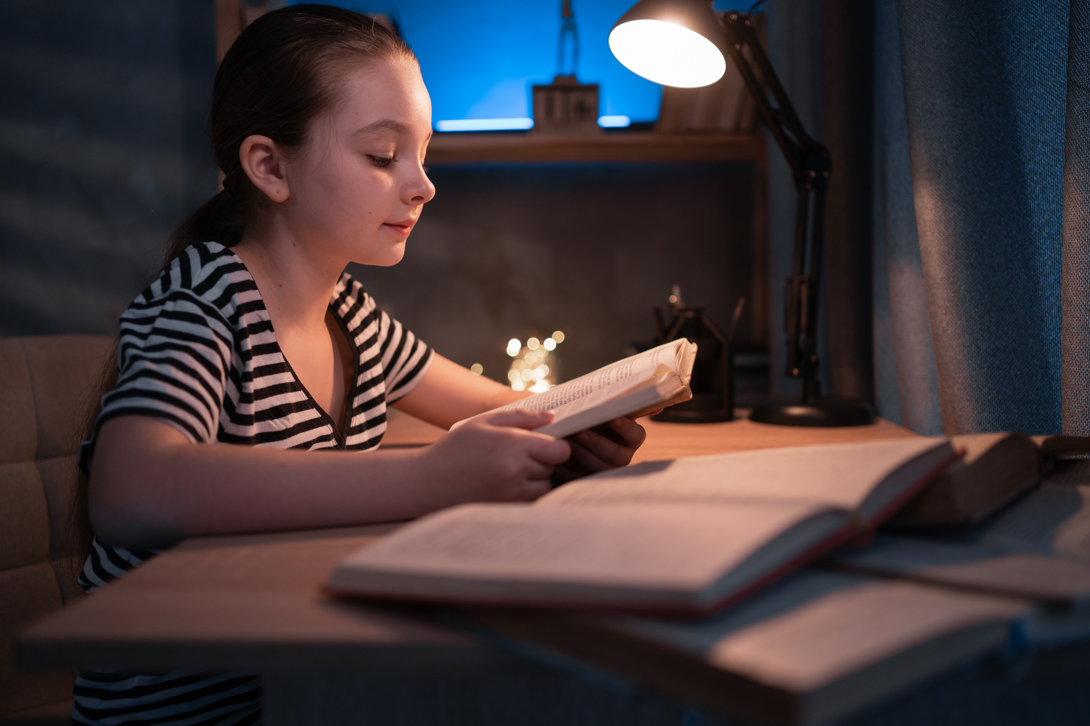 Bambina legge un libro seduta alla scrivania