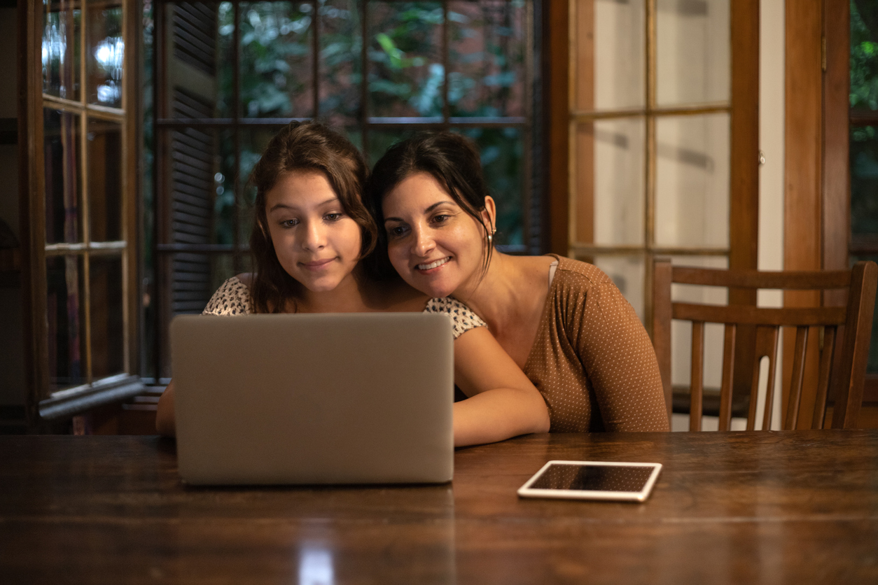 Una bambina e sua madre sedute al tavolo usano un tablet