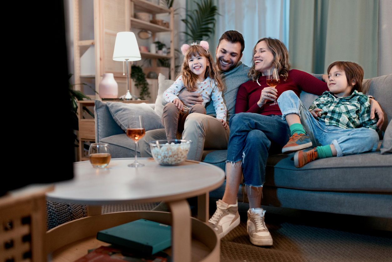 Bambino e bambina guardano una serie tv mentre in genitori sono sul divano