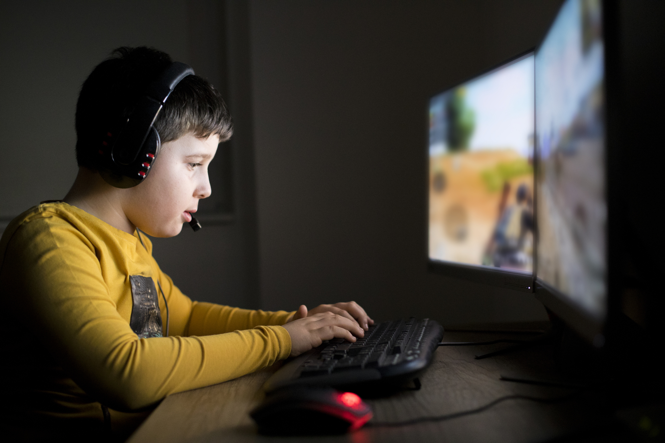 Un bambino seduto alla scrivania che gioca a un videogioco al computer
