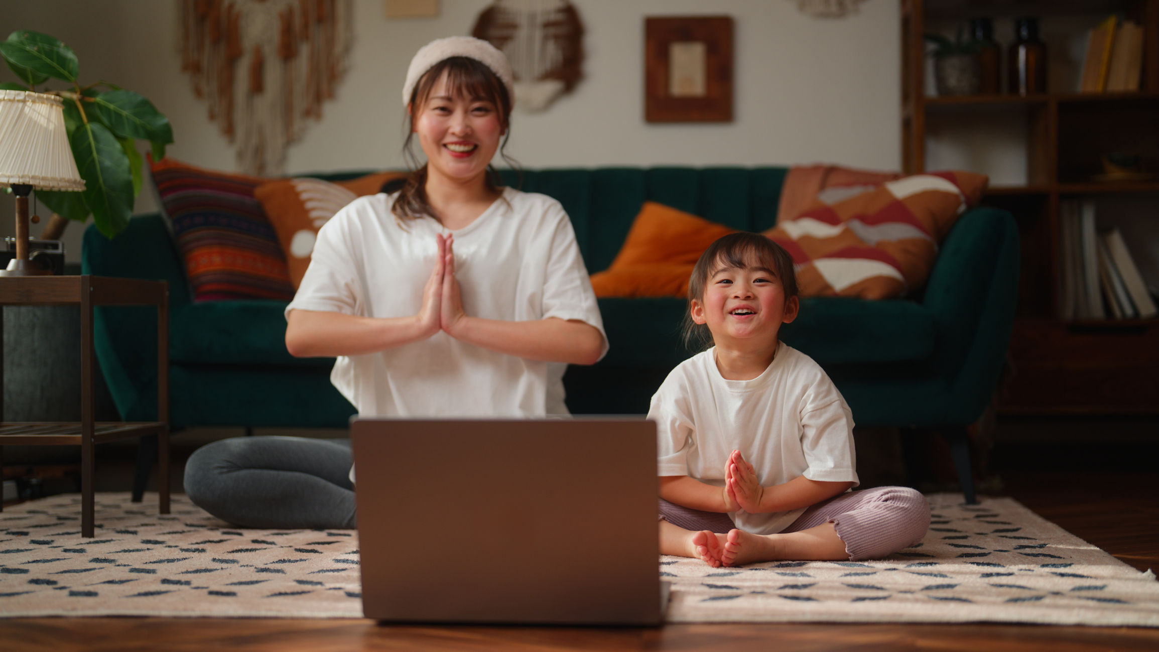 Una donna e una bambina fanno yoga su un tappetino con dispositivo digitale