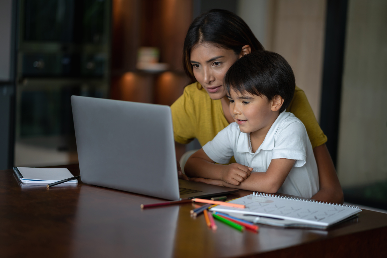 Una donna e un bambino seduti a tavola di fronte a un laptop