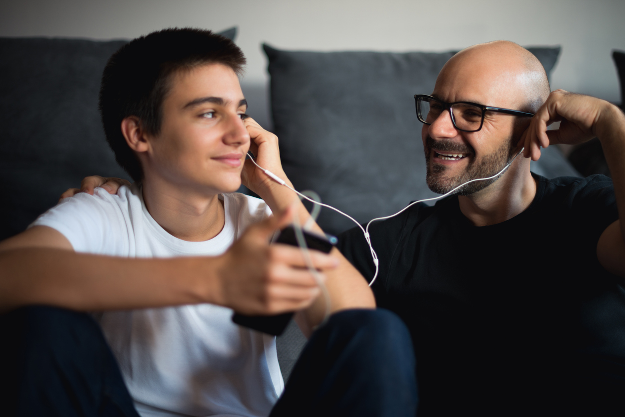 Un uomo e un ragazzino ascoltano insieme qualcosa tramite smartphone