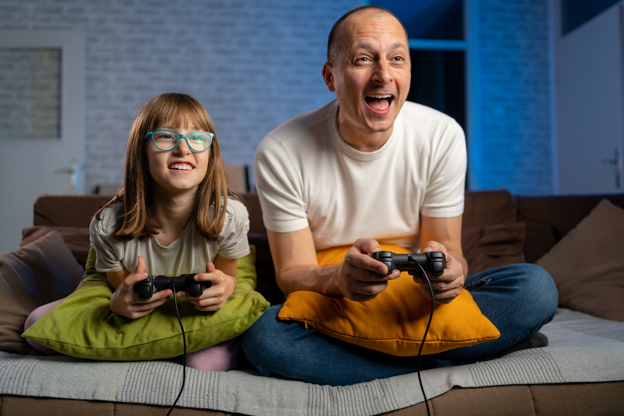 Padre e figlia seduti sul divano giocano ai videogiochi