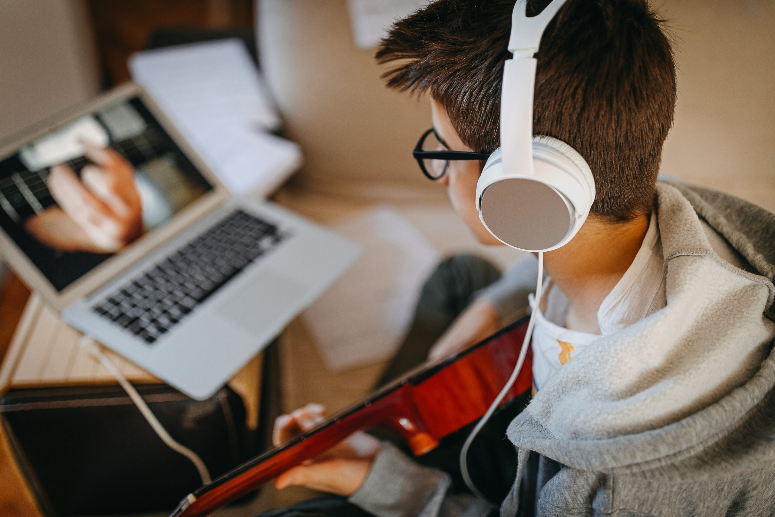 Un ragazzino suona la chitarra davanti a uno schermo di computer