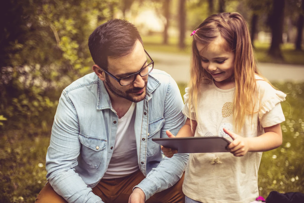 Un uomo e una bambina con dispositivo digitale